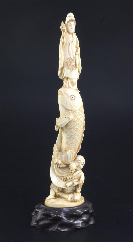 A Japanese ivory okimono of Kwannon standing upon a giant carp, early 20th century, 24.3cm, wood stand